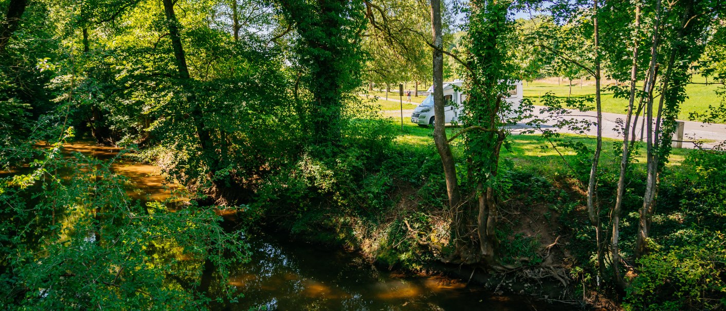 Ein Wohnmobil steht auf einem Stellplatz in Backnang, umgeben von B&auml;umen und einem Fluss. Die Umgebung ist gr&uuml;n und idyllisch., &copy; SMG, Thomas Niederm&uuml;ller