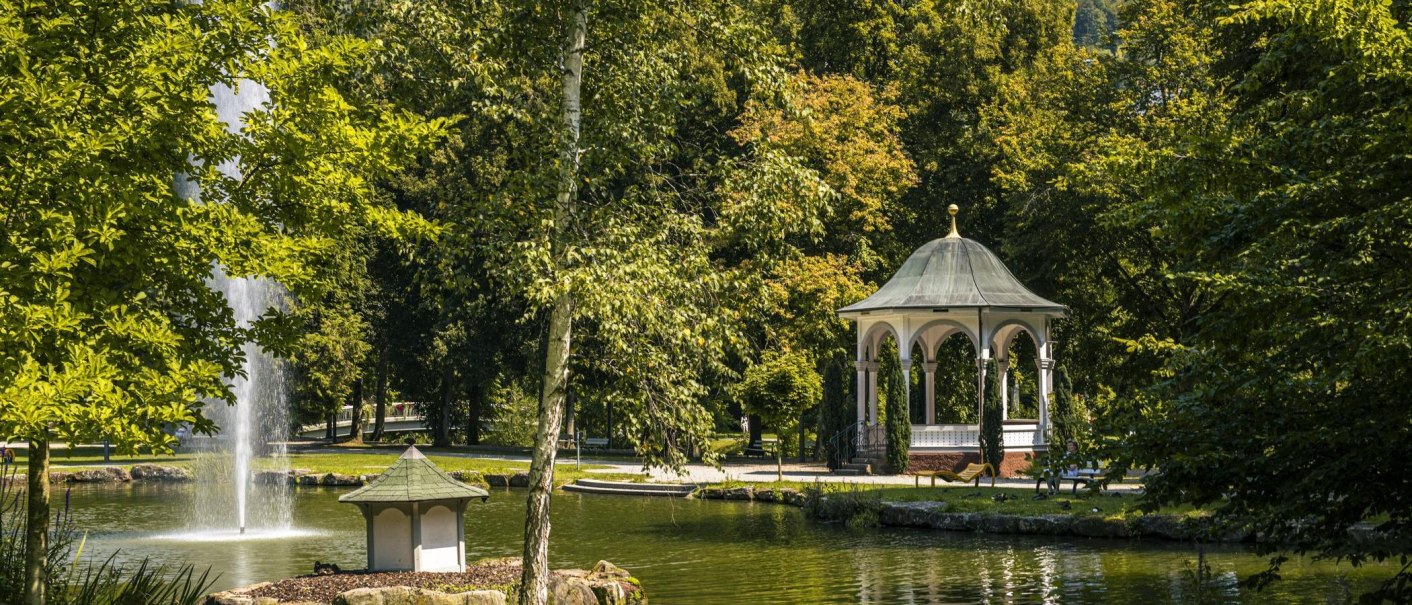 Ein Pavillon im Kurpark von Bad Liebenzell, umgeben von Bäumen und einem Teich mit Springbrunnen., © Stuttgart-Marketing GmbH, Sarah Schmid Ein Pavillon im Kurpark von Bad Liebenzell, umgeben von Bäumen und einem Teich mit Springbrunnen., © Stuttgart-Marketing GmbH, Sarah Schmid