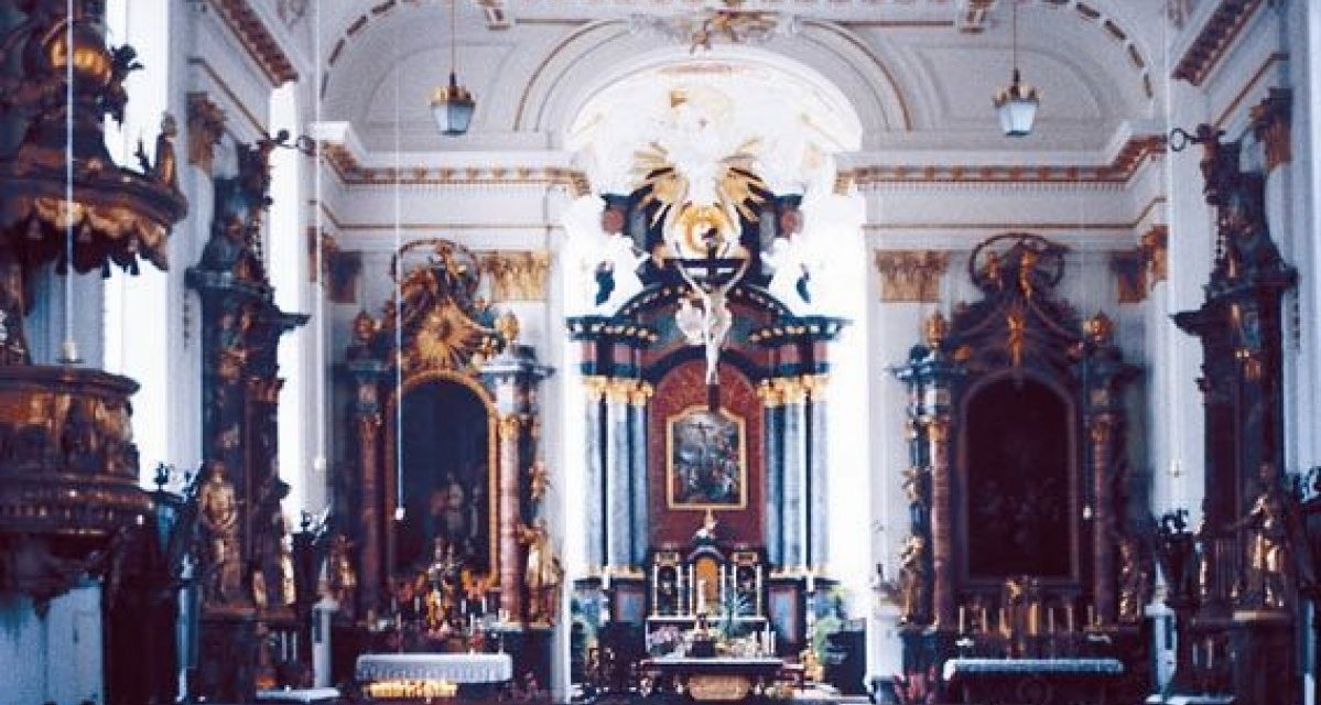 Innenansicht der Stiftskirche St. Cyriakus mit prächtigem Altar, goldenen Verzierungen und hohen Decken. Die Architektur ist reich dekoriert., © Stadt Wiesensteig Innenansicht der Stiftskirche St. Cyriakus mit prächtigem Altar, goldenen Verzierungen und hohen Decken. Die Architektur ist reich dekoriert., © Stadt Wiesensteig