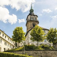 Der Backnanger Stadtturm ragt &uuml;ber Fachwerkh&auml;user und B&auml;ume unter blauem Himmel., &copy; SMG, Sarah Schmid