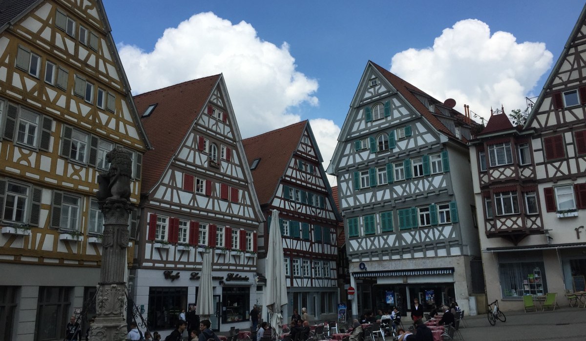 Fachwerkhäuser am Marktplatz in Herrenberg, Deutschland. Menschen sitzen in einem Café neben einem Brunnen. Der Himmel ist blau mit Wolken., © www.pro-cycl.de Fachwerkhäuser am Marktplatz in Herrenberg, Deutschland. Menschen sitzen in einem Café neben einem Brunnen. Der Himmel ist blau mit Wolken., © www.pro-cycl.de