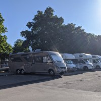 Wohnmobilstellplatz mit mehreren geparkten Wohnmobilen unter B&auml;umen bei Sonnenschein., &copy; Stadtverwaltung Weil der Stadt
