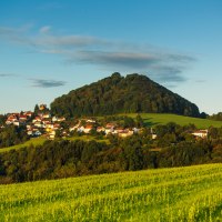 Der Berg Hohenstaufen erhebt sich hinter einem Dorf, umgeben von grünen Feldern und Bäumen, unter einem klaren blauen Himmel., © Landkreis Göppingen