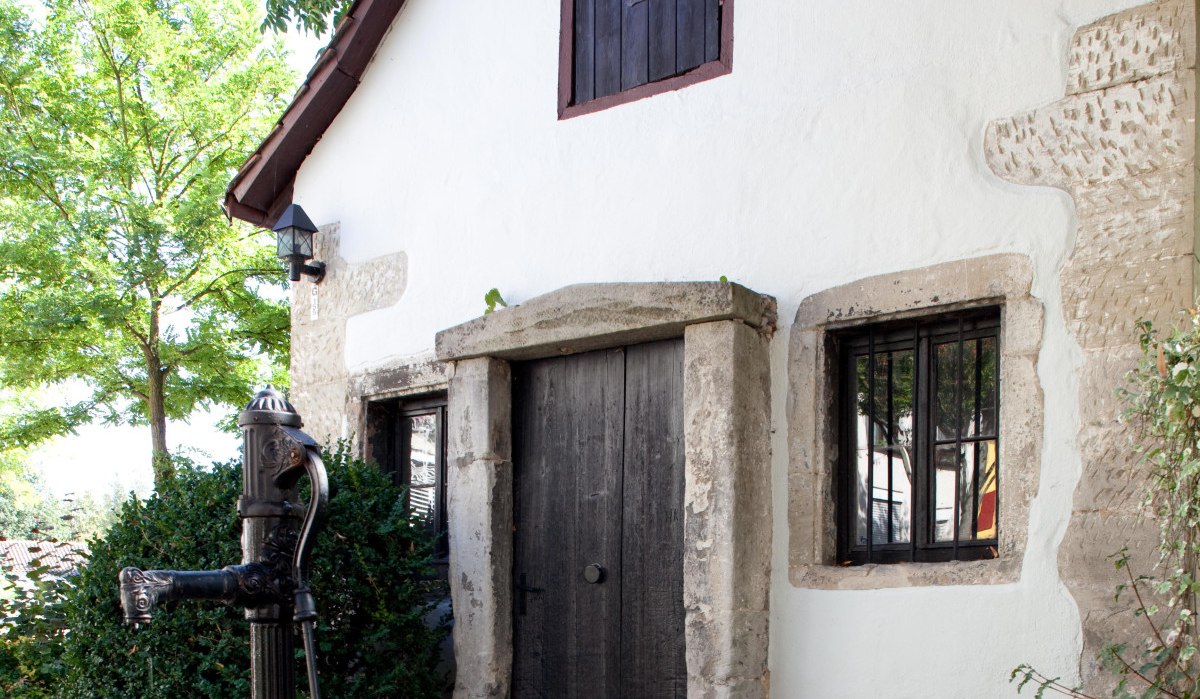 Kleines weißes Haus mit Holztür und Fensterläden, davor eine alte Wasserpumpe auf gepflastertem Weg. Umgeben von Bäumen und Sträuchern., © Waiblingen - Stuttgart-Marketing GmbH Kleines weißes Haus mit Holztür und Fensterläden, davor eine alte Wasserpumpe auf gepflastertem Weg. Umgeben von Bäumen und Sträuchern., © Waiblingen - Stuttgart-Marketing GmbH