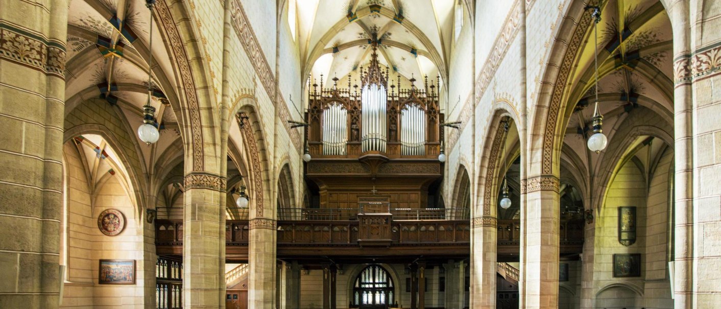Innenansicht der Amanduskirche in Bad Urach. Sicht auf die Orgel und gotische B&ouml;gen mit kunstvollen Verzierungen und h&auml;ngenden Lampen., &copy; Stuttgart-Marketing GmbH, Sarah Schmid