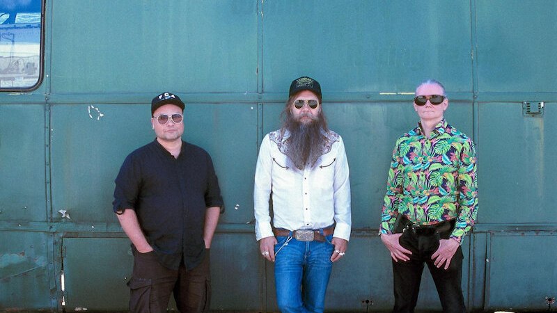 Drei Männer posieren lässig vor einem blauen Bus. Sie tragen Sonnenbrillen und unterschiedliche Outfits, darunter ein buntes Hemd und eine weiße Jacke., © Jazzclub Schwäbisch Hall e.V. Drei Männer posieren lässig vor einem blauen Bus. Sie tragen Sonnenbrillen und unterschiedliche Outfits, darunter ein buntes Hemd und eine weiße Jacke., © Jazzclub Schwäbisch Hall e.V.