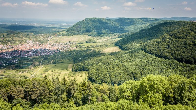 Blick von der Burg Hohenneuffen auf das Dorf Beuren, umgeben von gr&uuml;nen W&auml;ldern und H&uuml;geln unter einem blauen Himmel mit wenigen Wolken., &copy; hochgehberge