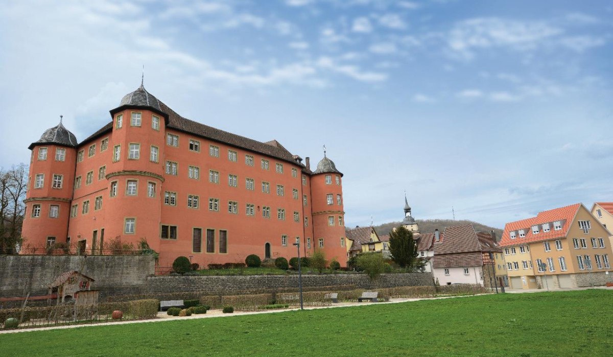 Schloss Künzelsau mit roter Fassade und Türmen, umgeben von grüner Wiese und angrenzenden Gebäuden unter blauem Himmel., © Würth Elektronik, Niedernhall Schloss Künzelsau mit roter Fassade und Türmen, umgeben von grüner Wiese und angrenzenden Gebäuden unter blauem Himmel., © Würth Elektronik, Niedernhall