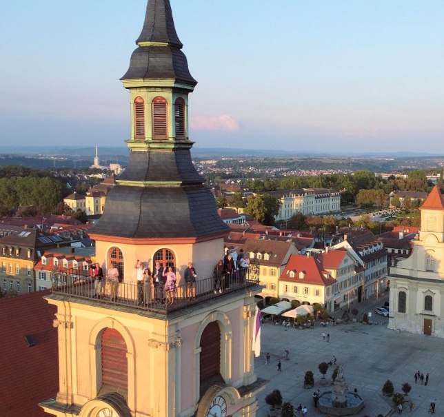 Menschen genie&szlig;en den Ausblick vom Kirchturm auf den Ludwigsburger Marktplatz im warmen Abendlicht. Historische Geb&auml;ude und eine weite Landschaft sind sichtbar., &copy; Copyright: Tourismus & Events Ludwigsburg, Fotograf: ArtusTV