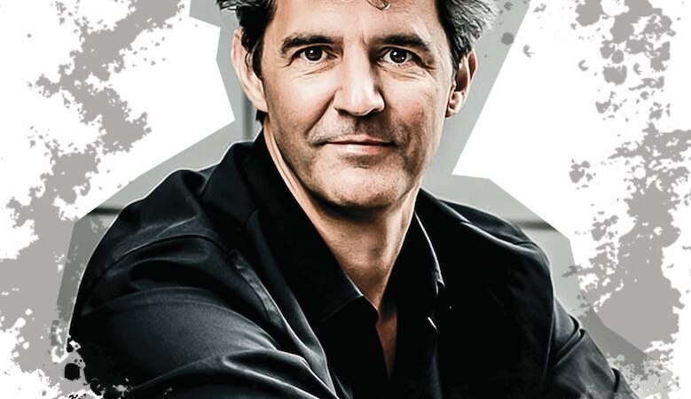 Ein Mann mit dunklem Haar und schwarzem Hemd vor einem abstrakten, gesprenkelten Hintergrund., © Mauerwerk GmbH