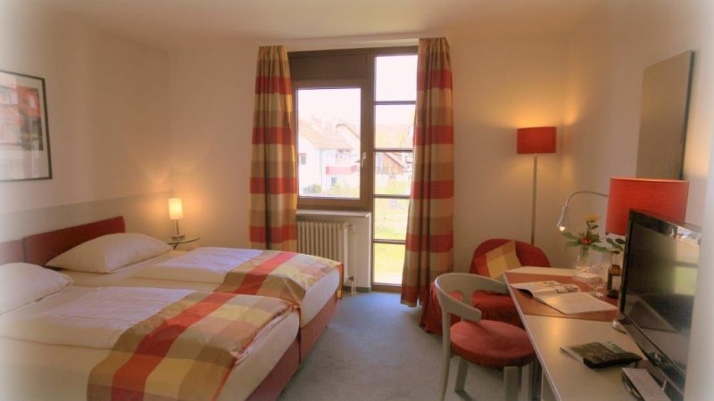 Gemütliches Doppelzimmer mit zwei Betten, Schreibtisch, Fernseher und Fenster mit gestreiften Vorhängen. Helle, einladende Atmosphäre., © Hotel Körschtal Gemütliches Doppelzimmer mit zwei Betten, Schreibtisch, Fernseher und Fenster mit gestreiften Vorhängen. Helle, einladende Atmosphäre., © Hotel Körschtal
