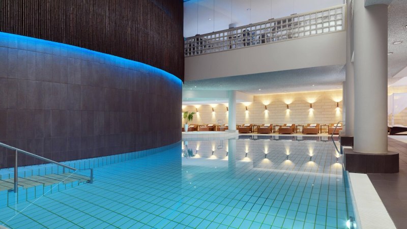 Moderner Hotelpool mit blauer Beleuchtung, Liegestühle im Hintergrund, stilvolle Architektur., © Hotel Le Méridien Moderner Hotelpool mit blauer Beleuchtung, Liegestühle im Hintergrund, stilvolle Architektur., © Hotel Le Méridien