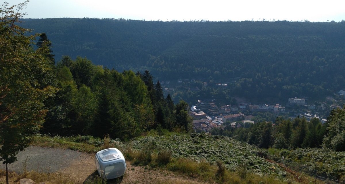 Ein kleiner Wohnwagen steht auf einem H&uuml;gel mit Blick auf ein Tal und eine Stadt, umgeben von dichtem Wald., &copy; N&ouml;rdlicher Schwarzwald