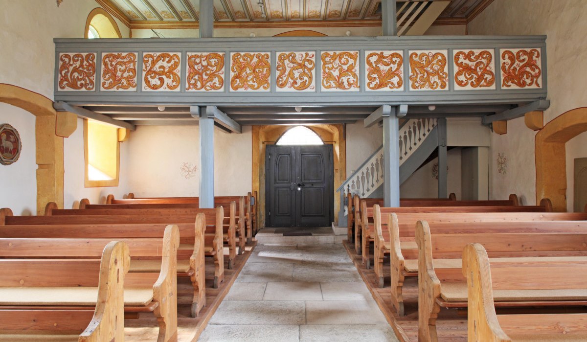 Innenansicht der Nikolauskirche in Waiblingen-Hegnach. Holzbänke, bemalte Decke und eine Empore mit verzierten Paneelen sind sichtbar., © Waiblingen - Stuttgart-Marketing GmbH Innenansicht der Nikolauskirche in Waiblingen-Hegnach. Holzbänke, bemalte Decke und eine Empore mit verzierten Paneelen sind sichtbar., © Waiblingen - Stuttgart-Marketing GmbH