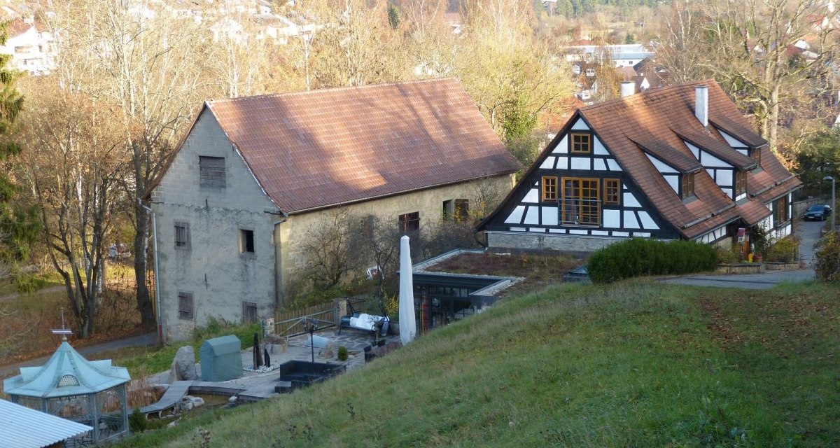 Ein Fachwerkhaus und ein altes Gebäude stehen in einer ländlichen Umgebung. Im Hintergrund sind Bäume und eine Siedlung zu sehen., © Natur.Nah. Schönbuch & Heckengäu Ein Fachwerkhaus und ein altes Gebäude stehen in einer ländlichen Umgebung. Im Hintergrund sind Bäume und eine Siedlung zu sehen., © Natur.Nah. Schönbuch & Heckengäu