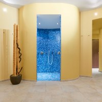 Ein Spa-Bereich mit einer blauen Mosaikdusche in der Mitte, umgeben von gelben Wänden und dekorativen Bambusstäben., © TOMAS