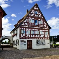 Fachwerkhaus in Plochingen mit rotem und weißem Muster, blauer Himmel und gepflasterter Platz im Vordergrund., © Thomas Pressel
