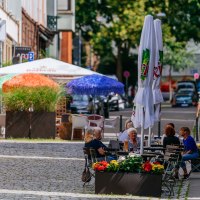 Gem&uuml;tliche Stra&szlig;enszene im Bohnenviertel mit Caf&eacute;s, bunten Sonnenschirmen und Menschen, die im Freien sitzen. Pflastersteine und gr&uuml;ne Pflanzen s&auml;umen den Weg., &copy; SMG Thomas Niederm&uuml;ller