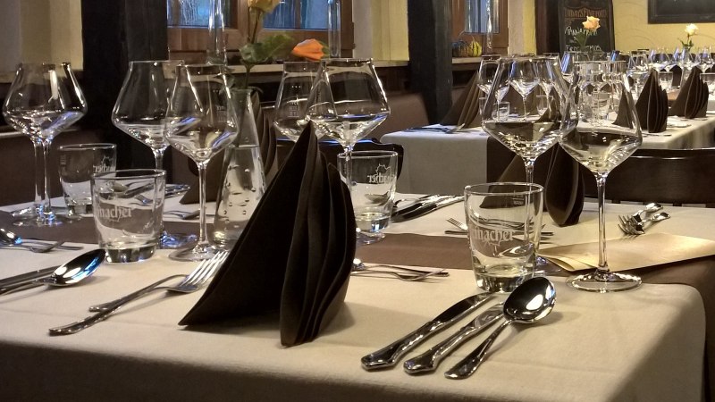 Elegante Tischdekoration in einem Restaurant mit Weingläsern, Besteck und gefalteten Servietten auf weißen Tischdecken., © Wirtshaus zom Schiller Fellbach Elegante Tischdekoration in einem Restaurant mit Weingläsern, Besteck und gefalteten Servietten auf weißen Tischdecken., © Wirtshaus zom Schiller Fellbach