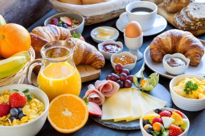 Ein reich gedeckter Frühstückstisch mit Croissants, Obst, Käse, Schinken, Eiern, Müsli und Orangensaft., © Cool-Tours StattReisen