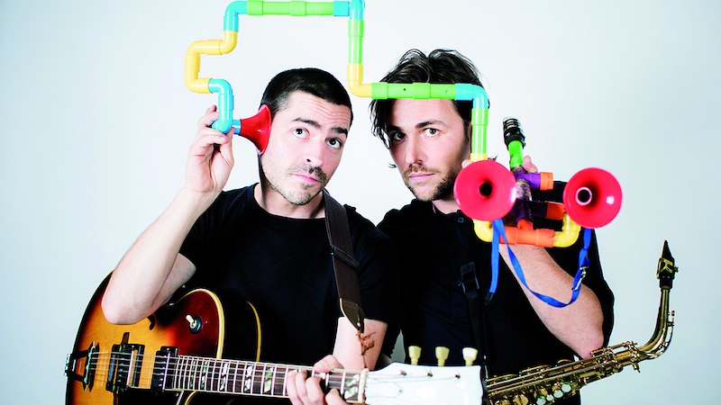 Zwei Männer mit Gitarre und Saxophon halten buntes Spielzeug an den Köpfen. Einer hat eine Gitarre, der andere ein Saxophon. Humorvolle Szene., © Kulturbüro Schwäbisch Gmünd