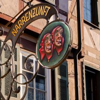 Ein kunstvoll gestaltetes Schild der Narrenzunft h&auml;ngt an einem Fachwerkhaus in Weil der Stadt. Es zeigt zwei Masken mit roten Kopft&uuml;chern., &copy; Olivia + RichiPhotoart