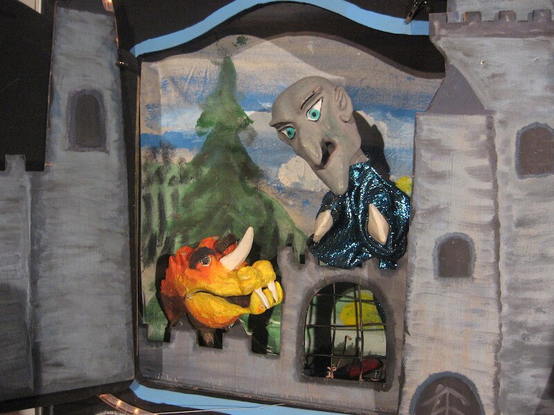 Puppentheater mit einem Zauberer und einem Drachen in einer Burgkulisse. Der Zauberer trägt ein glitzerndes blaues Gewand., © Prinzessin Gisela Theater