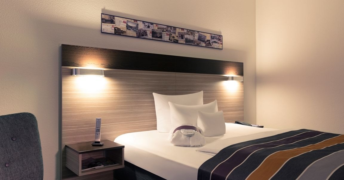 Modernes Hotelzimmer mit Doppelbett, gestreifter Bettdecke, zwei Wandlampen und einem dekorativen Bild über dem Bett., © Mercure Hotel Stuttgart Gerlingen Modernes Hotelzimmer mit Doppelbett, gestreifter Bettdecke, zwei Wandlampen und einem dekorativen Bild über dem Bett., © Mercure Hotel Stuttgart Gerlingen
