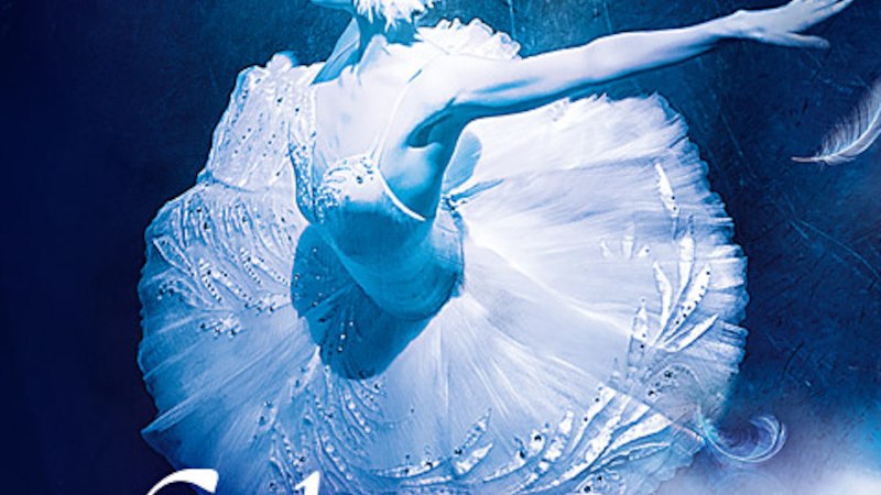 Eine Ballerina in einem weißen Tutu tanzt anmutig auf der Bühne, umgeben von blauen Lichteffekten und schwebenden Federn., © P.T.F. GmbH-Konzertagentur Friedmann Eine Ballerina in einem weißen Tutu tanzt anmutig auf der Bühne, umgeben von blauen Lichteffekten und schwebenden Federn., © P.T.F. GmbH-Konzertagentur Friedmann