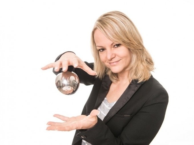 Frau mit blonden Haaren hält eine Glaskugel in den Händen und lächelt. Sie trägt einen schwarzen Blazer vor weißem Hintergrund., © Cool-Tours StattReisen Frau mit blonden Haaren hält eine Glaskugel in den Händen und lächelt. Sie trägt einen schwarzen Blazer vor weißem Hintergrund., © Cool-Tours StattReisen