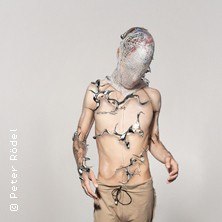 Person mit futuristischem, metallischem Körperschmuck und Maske vor grauem Hintergrund., © links im Bild Person mit futuristischem, metallischem Körperschmuck und Maske vor grauem Hintergrund., © links im Bild