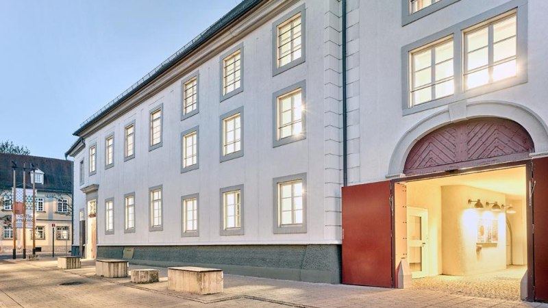 Ein Museumsgeb&auml;ude mit beleuchteten Fenstern und offenem Tor bei D&auml;mmerung. Der Eingang ist einladend erleuchtet., &copy; Ludwigsburg Museum