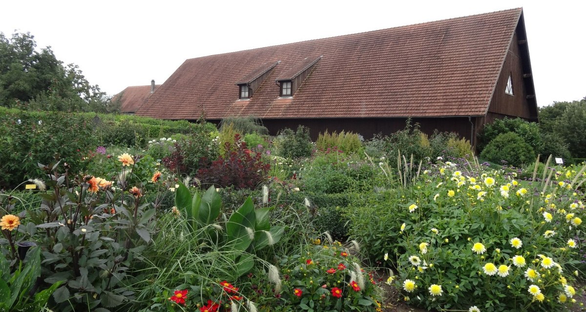 Bunter Blumengarten vor einem traditionellen Bauernhaus mit rotem Ziegeldach und Holzwänden., © Nürtingen - Stuttgart-Marketing GmbH