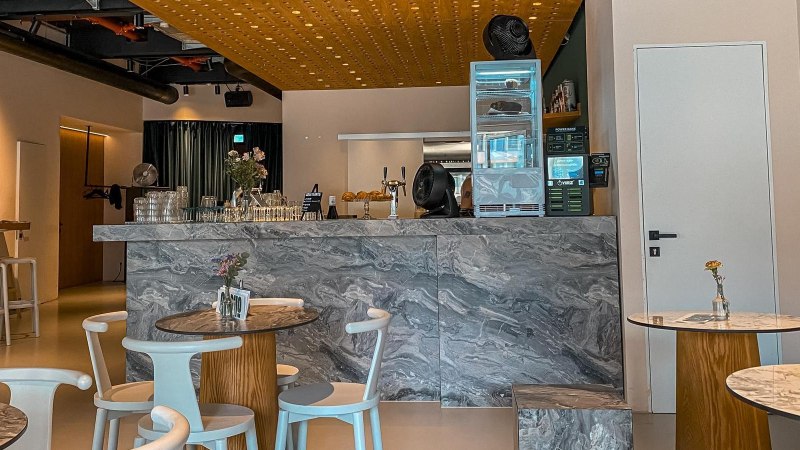 Modernes Caf&eacute; mit Marmortischen und einer stilvollen Theke. Dezente Beleuchtung und minimalistische Dekoration schaffen eine einladende Atmosph&auml;re., &copy; SMG