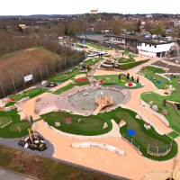 Luftaufnahme eines Adventure-Golfplatzes in Vaihingen mit grünen Bahnen, Hindernissen und einem zentralen Teich. Menschen spielen auf dem Platz., © TV Vaihingen/Enz