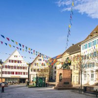Der Marktplatz von Weil der Stadt zeigt historische Geb&auml;ude und bunte Wimpel unter blauem Himmel. Eine Statue steht zentral auf dem Platz., &copy; SMG, Sarah Schmid