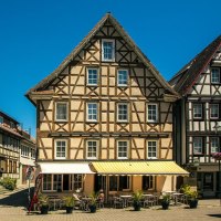 Fachwerkh&auml;user am Marktplatz von Murrhardt unter klarem, blauem Himmel. Vor den Geb&auml;uden stehen Tische und St&uuml;hle eines Caf&eacute;s., &copy; SMG, Sarah Schmid
