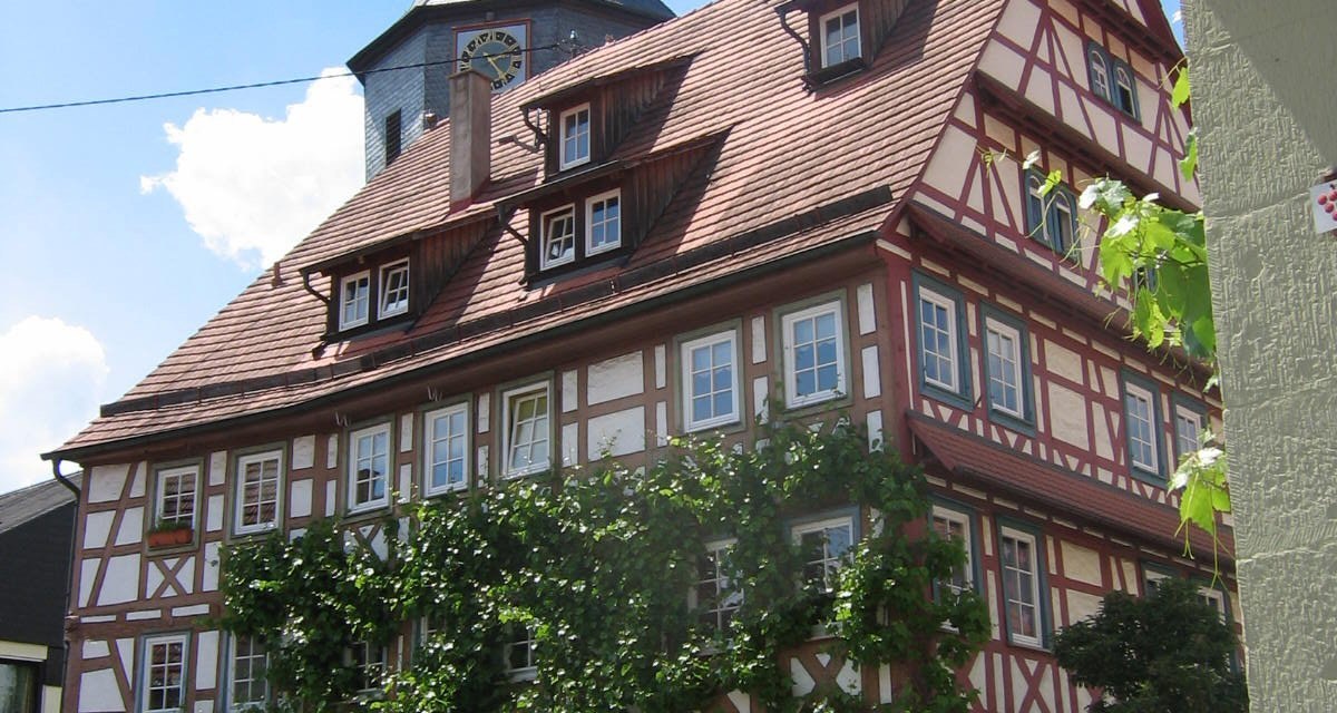 Fachwerkhaus mit roten Dachziegeln und Pflanzenbewuchs, im Hintergrund ein Kirchturm. Blauer Himmel mit wenigen Wolken., © Land der 1000 Hügel - Kraichgau-Stromberg Fachwerkhaus mit roten Dachziegeln und Pflanzenbewuchs, im Hintergrund ein Kirchturm. Blauer Himmel mit wenigen Wolken., © Land der 1000 Hügel - Kraichgau-Stromberg