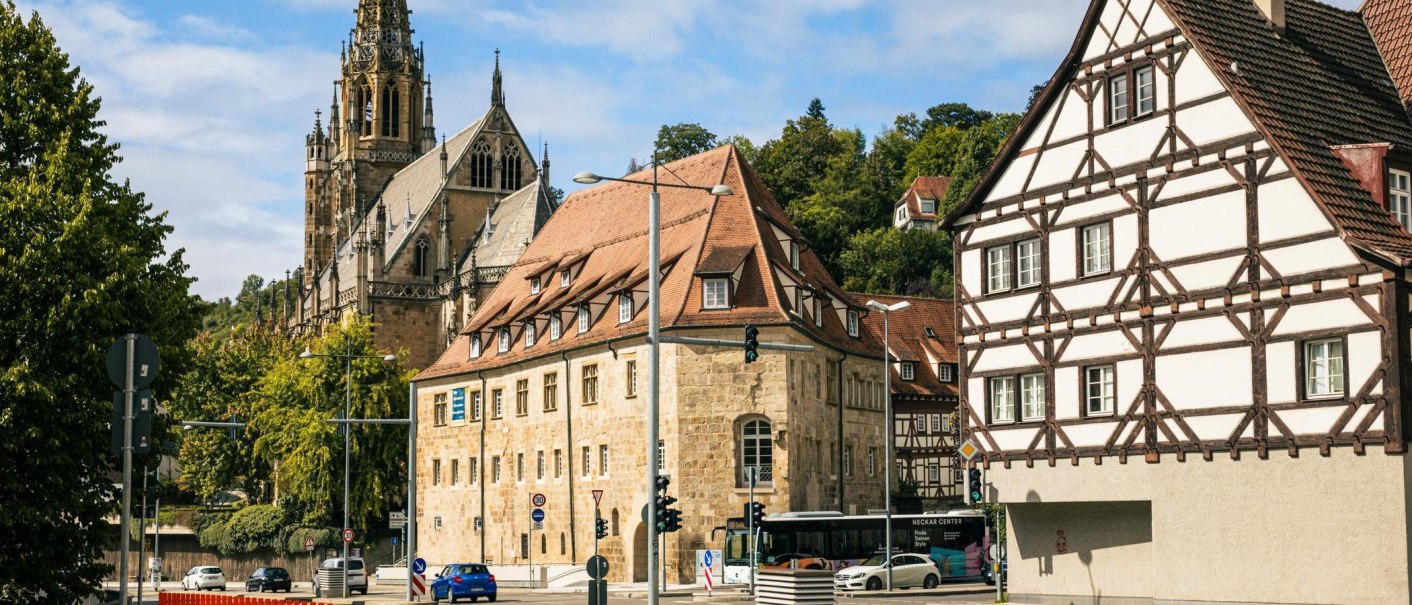 Historische Gebäude in Esslingen am Neckar, darunter Fachwerkhäuser und eine Kirche. Die Szene zeigt eine belebte Straßenecke mit Autos und Bussen., © SMG, Sarah Schmid Historische Gebäude in Esslingen am Neckar, darunter Fachwerkhäuser und eine Kirche. Die Szene zeigt eine belebte Straßenecke mit Autos und Bussen., © SMG, Sarah Schmid