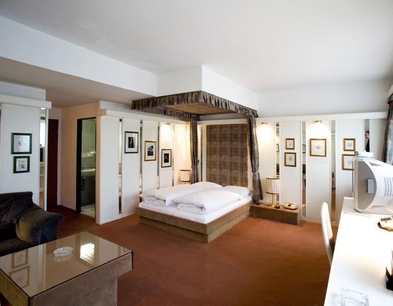 Ein geräumiges Hotelzimmer mit einem Himmelbett, Schreibtisch, Sofa und dekorativen Bildern an den Wänden., © Hotel Spahr Ein geräumiges Hotelzimmer mit einem Himmelbett, Schreibtisch, Sofa und dekorativen Bildern an den Wänden., © Hotel Spahr