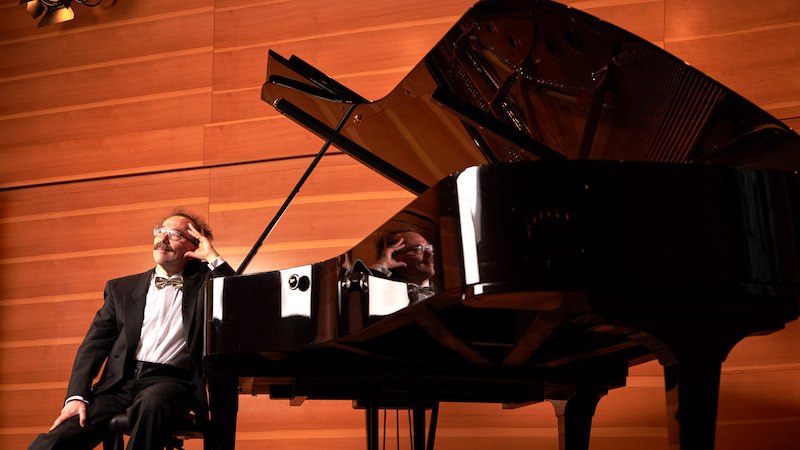 Ein Pianist sitzt nachdenklich an einem Fl&uuml;gel auf einer B&uuml;hne mit Holzverkleidung. Die Beleuchtung schafft eine warme Atmosph&auml;re., &copy; Stadtverwaltung Kirchheim unter Teck - Kulturring