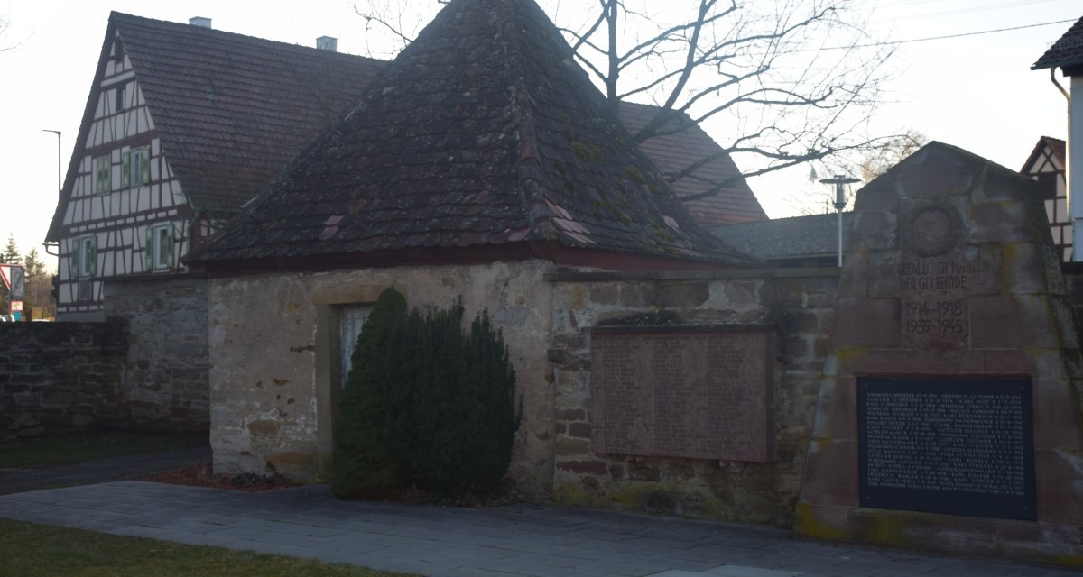 Gedenkstein und Tafeln auf einem ehemaligen Friedhof, umgeben von Fachwerkhäusern und Bäumen., © Land der 1000 Hügel - Kraichgau-Stromberg Gedenkstein und Tafeln auf einem ehemaligen Friedhof, umgeben von Fachwerkhäusern und Bäumen., © Land der 1000 Hügel - Kraichgau-Stromberg