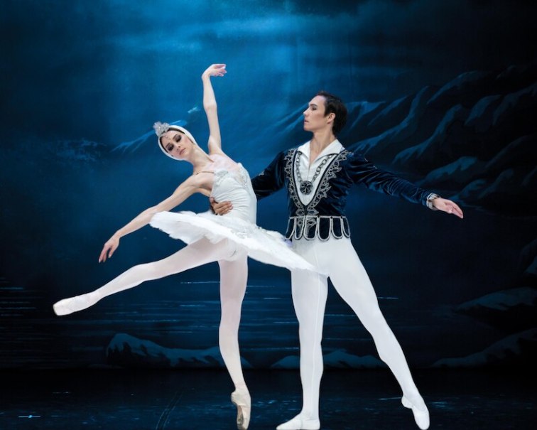 Zwei Balletttänzer in eleganten Kostümen führen eine Szene aus Schwanensee auf. Der Hintergrund zeigt eine nächtliche Landschaft., © Stadthalle Leonberg