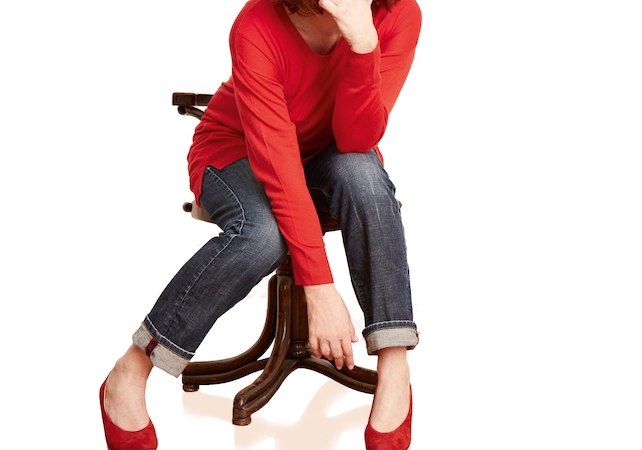 Frau mit roten Haaren, rotem Oberteil und Jeans sitzt lächelnd auf einem Stuhl. Sie trägt rote Schuhe und hat eine entspannte Haltung., © Stadtverwaltung Kirchheim unter Teck - Kulturring