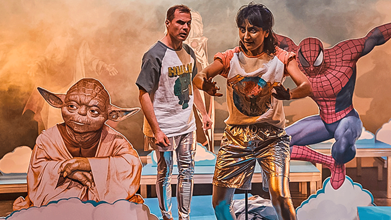 Zwei Personen auf einer B&uuml;hne mit Yoda, Spider-Man und Wonder Woman im Hintergrund. Die Szene wirkt fantasievoll und bunt., &copy; JES, Alex Wunsch