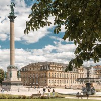 Der Schlossplatz in Stuttgart zeigt die Jubiläumssäule und das Neue Schloss. Menschen genießen den sonnigen Tag, während Bäume den Platz säumen., © SMG, Sarah Schmid Der Schlossplatz in Stuttgart zeigt die Jubiläumssäule und das Neue Schloss. Menschen genießen den sonnigen Tag, während Bäume den Platz säumen., © SMG, Sarah Schmid