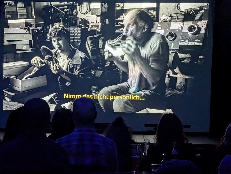 Menschen sitzen in einem Kino und schauen einen schwarz-weißen Film mit dem Untertitel: "Nimm das nicht persönlich..."., © Kulturhaus Schwanen Menschen sitzen in einem Kino und schauen einen schwarz-weißen Film mit dem Untertitel: "Nimm das nicht persönlich..."., © Kulturhaus Schwanen