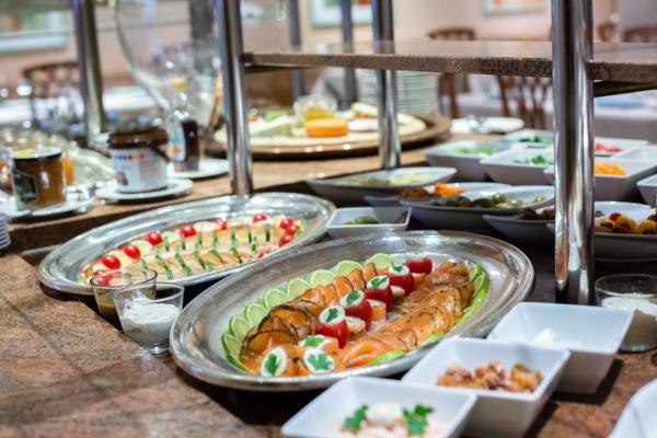 Frühstücksbuffet mit Lachs, Tomaten, Gurken und Beilagen auf einem Tisch., © Kronen Hotel GmbH Frühstücksbuffet mit Lachs, Tomaten, Gurken und Beilagen auf einem Tisch., © Kronen Hotel GmbH