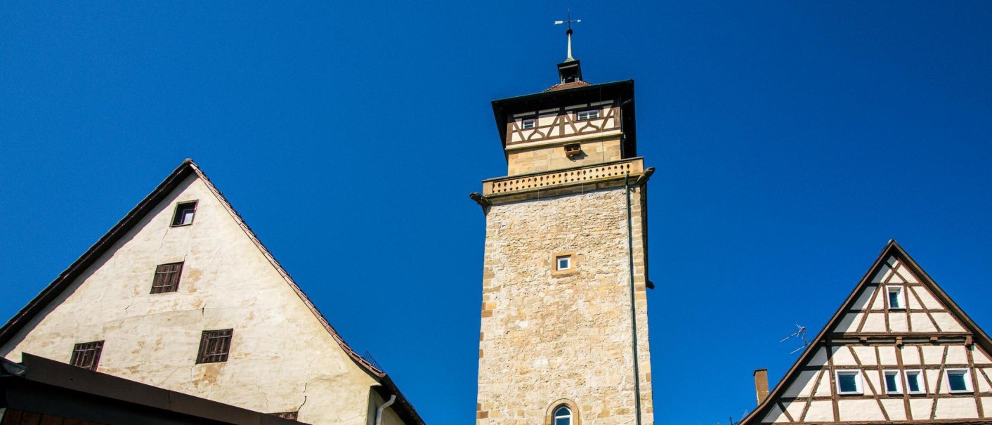 Der Hochwachturm in Waiblingen ragt zwischen zwei Fachwerkhäusern in den blauen Himmel empor., © SMG, Sarah Schmid Der Hochwachturm in Waiblingen ragt zwischen zwei Fachwerkhäusern in den blauen Himmel empor., © SMG, Sarah Schmid