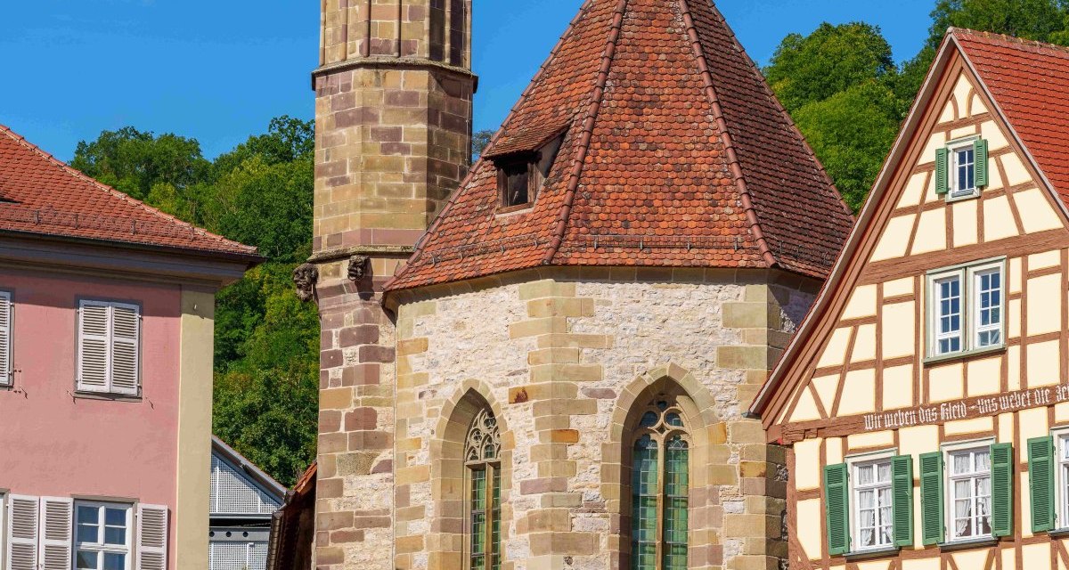 Die Johanniterkirche in Schw&auml;bisch Hall mit ihrem markanten Turm, umgeben von Fachwerkh&auml;usern und einem klaren blauen Himmel., &copy; Michael K&uuml;hneisen